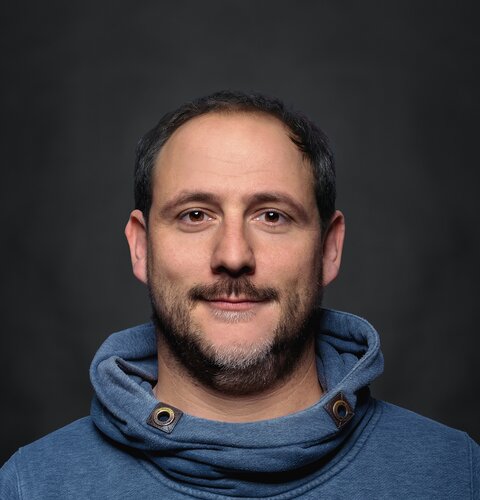 Das Bild ist ein Porträt von Christian Kierdorf. Er trägt einen hellblauen Pullover. Der Hintergrund ist dunkel. | © wob AG