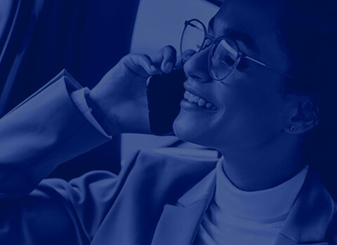 A woman in a suit and glasses can be seen in the crop, talking on the phone and gazing contentedly into the distance. A blue filter is placed over the image. | © wob AG